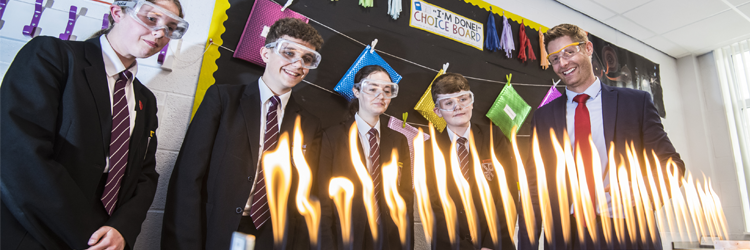 Photo of teacher with students, lighting burner in science class.